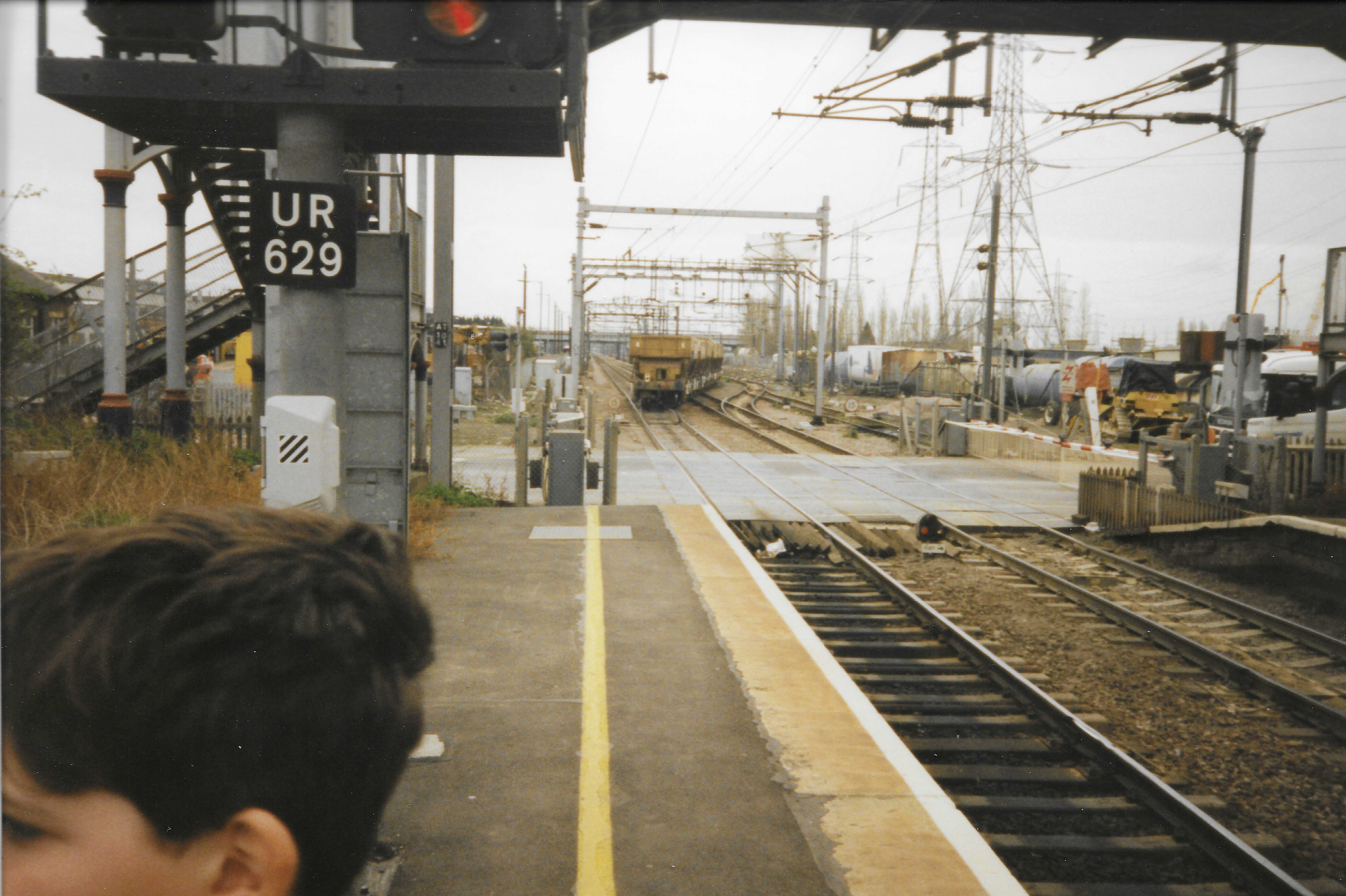 A train approaching along the railway beside a station platform